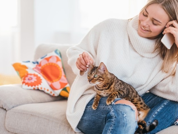 cosy-home-atmosphere-family-pet-girl-stroking-her-bengal-cat-while-talking-phone_201836-5507
